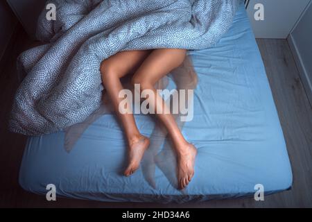 Frau, die im Bett schläft und an RLS oder ruhelosen Beinen leidet Stockfoto