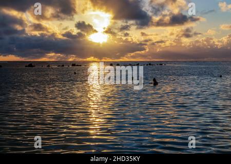 Honolulu, Hawaii - 2. Dezember 2021: Sonnenuntergang am Meer vom Ala Moana Beach und Regional Park aus gesehen. Die Menschen genießen den warmen Abend Stockfoto