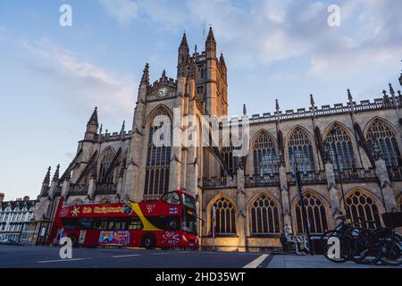 Roter Bus mit offenem Oberdeck, vorbei an der mittelalterlichen gotischen Fassade der Bath Abbey in der historischen Weltkulturerbestätte Bath, Somerset, England, Großbritannien Stockfoto
