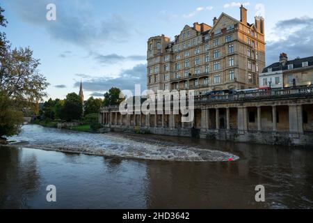 Das Empire Hotel und die Grand Parade Kolonnade, die sich über dem Fluss Avon Wehr in der historischen Weltkulturerbestätte Bath, Somerset, England, erhebt Stockfoto