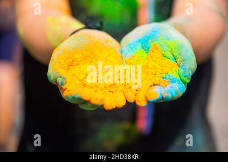 Nahaufnahme der Hände, die einen Haufen von farbigem orangefarbenem Pulver halten Stockfoto