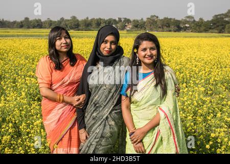 Dhaka, Bangladesch. 31st Dez 2021. Frauen posieren für ein Foto auf einem gelben Senffeld am Stadtrand von Dhaka. Senf ist eine Ernte bei kühlem Wetter und wird aus Samen, die im frühen Frühjahr gesät wurden, angebaut. Von Mitte Dezember bis Ende Januar kultivieren die bangladeschischen Bauern ihre Ernte von leuchtend bunten gelben Senfblüten, die in voller Blüte stehen. (Foto: Sazzad Hossain/SOPA Images/Sipa USA) Quelle: SIPA USA/Alamy Live News Stockfoto