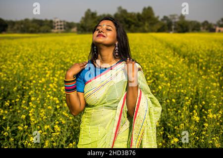 Dhaka, Bangladesch. 31st Dez 2021. Eine Frau posiert für ein Foto auf einem gelben Senffeld am Stadtrand von Dhaka. Senf ist eine Ernte bei kühlem Wetter und wird aus Samen gezüchtet, die im frühen Frühjahr, von Mitte Dezember bis Ende Januar, von bangladeschischen Landwirten angebaut werden, die ihre Früchte von leuchtend bunten gelben Senfblüten in voller Blüte haben. (Foto: Sazzad Hossain/SOPA Images/Sipa USA) Quelle: SIPA USA/Alamy Live News Stockfoto