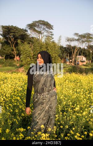 Dhaka, Bangladesch. 31st Dez 2021. Eine Frau posiert für ein Foto auf einem gelben Senffeld am Rande von Dhaka.Senf ist eine Ernte bei kühlem Wetter und wird aus Samen gezüchtet, die im frühen Frühjahr, von Mitte Dezember bis Ende Januar, gesät wurden. Die bangladeschischen Bauern kultivieren ihre Ernte aus leuchtend bunten gelben Senfblüten, die in voller Blüte stehen. (Bild: © Sazzad Hossain/SOPA Images via ZUMA Press Wire) Stockfoto