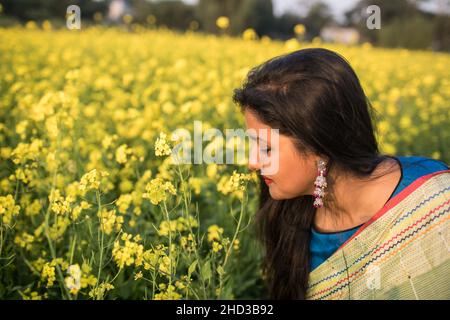 Dhaka, Bangladesch. 31st Dez 2021. Eine Frau posiert für ein Foto auf einem gelben Senffeld am Rande von Dhaka.Senf ist eine Ernte bei kühlem Wetter und wird aus Samen gezüchtet, die im frühen Frühjahr, von Mitte Dezember bis Ende Januar, gesät wurden. Die bangladeschischen Bauern kultivieren ihre Ernte aus leuchtend bunten gelben Senfblüten, die in voller Blüte stehen. (Bild: © Sazzad Hossain/SOPA Images via ZUMA Press Wire) Stockfoto