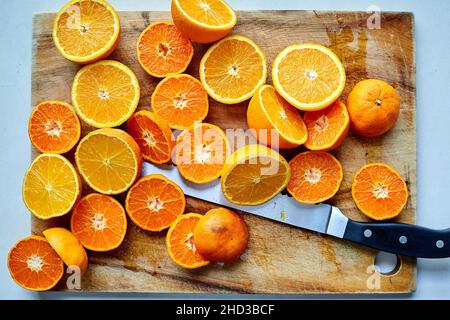 Orangefarbene Hälften auf Schneidebrett mit Messer Stockfoto