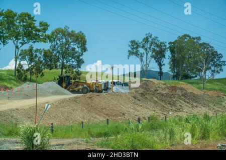 Bruce Highway, Proserpine, Queensland, Australien - Dezember 2021: Schwere Maschinen für Straßenbauarbeiten auf der Autobahn parkten inmitten von Kies an der Seite Stockfoto