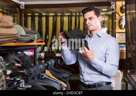 Männlicher Jäger, der Jagdausrüstung im Fachgeschäft wählt Stockfoto