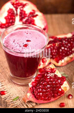 Saftiger Granatapfel und seine Hälfte mit LaubnSchöne Komposition mit saftigen Granatäpfeln, auf altem Holztisch Stockfoto