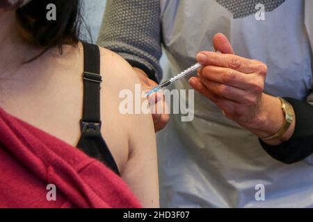 Eine Gesundheitsarbeiterin des Nationalen Gesundheitsdienstes (NHS) verabreicht einer Frau in einem Impfzentrum einen Pfizer/BioNTech Covid-19-Auffrischungsimpfstoff. Stockfoto