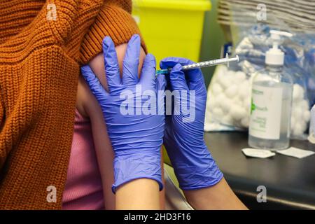 Eine Gesundheitsarbeiterin des Nationalen Gesundheitsdienstes (NHS) verabreicht einer Frau in einem Impfzentrum einen Pfizer/BioNTech Covid-19-Auffrischungsimpfstoff. Stockfoto