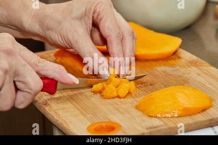 Cook schneidet saftige Mango in Scheiben, um Salat zuzubereiten Stockfoto