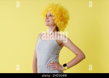Fröhliche junge Frau in gelber Perücke, die im Studio steht Stockfoto