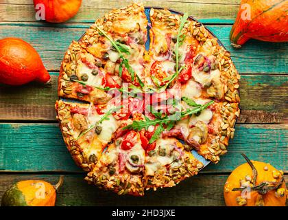 Pizza mit Salami, Käse, Tomate auf einem Kürbis-Fladenbrot. Herbstrezept Stockfoto