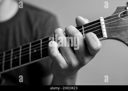 Männer fangen Akkorde lernen Gitarre zu spielen. Closeup-Musiker fangen Gitarrenakkorde. Männliche Musiker halten Akkorde und Strum Gitarre. Stockfoto