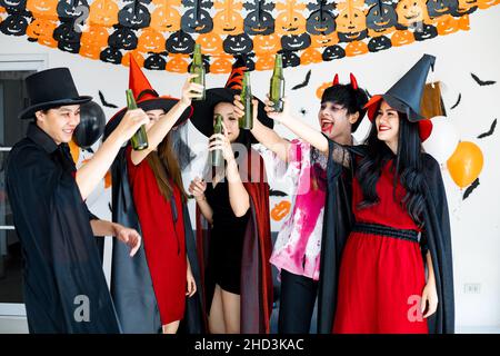 Bande von jungen Asiaten in Kostüm Hexe, Zauberer mit feiern Halloween-Party zum Tanzen und Trinken und betrunken im Zimmer. Gruppe teen Thai mit feiern Stockfoto