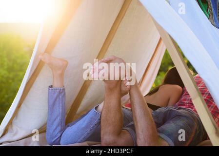 Wanderer pärchen Camping in der Natur. Rückbeine Ansicht des Paares im Zelt. Bester Freund. Konzentrieren Sie sich auf die Füße. Romantische Liebhaber im Urlaub Camping im Zelt. Paare Stockfoto