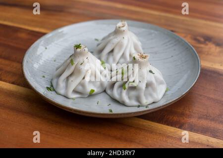 Nationale georgische Küche. Khinkali mit Fleisch. Khinkali auf dem Teller auf dem hölzernen Hintergrund. Draufsicht, Nahaufnahme mit Kopierbereich. Hochwertige Fotos Stockfoto