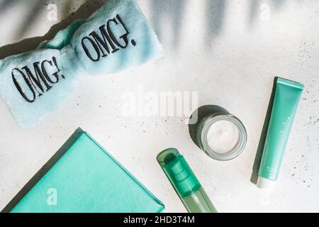 Gläser kosmetische Creme mit grünen Blättern, omg Haarband und Notizbuch minzfarben auf weiß mit Schatten, Oberkante Stockfoto