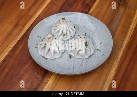 Nationale georgische Küche. Khinkali mit Fleisch. Khinkali auf dem Teller auf dem hölzernen Hintergrund. Draufsicht, Nahaufnahme mit Kopierbereich. Hochwertige Fotos Stockfoto