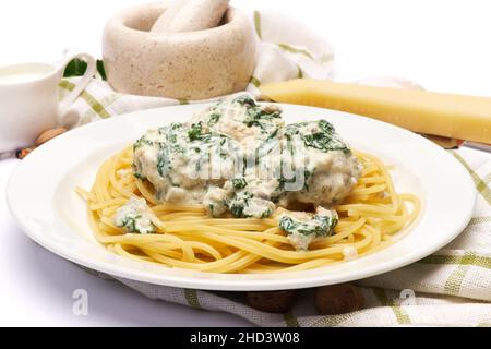 Portion leckere Fleischbällchen mit Spinat in cremiger Sauce und Pasta Stockfoto