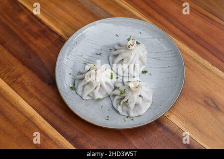 Nationale georgische Küche. Khinkali mit Fleisch. Khinkali auf dem Teller auf dem hölzernen Hintergrund. Draufsicht, Nahaufnahme mit Kopierbereich. Hochwertige Fotos Stockfoto
