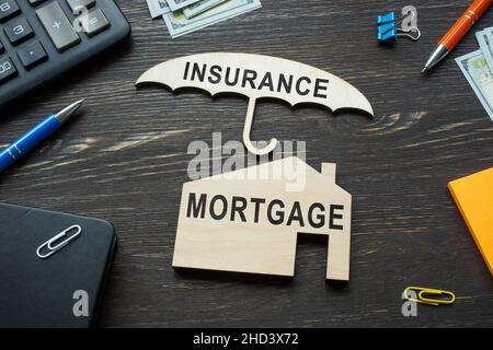 Hypothekenversicherungskonzept. Holzschirm und kleines Haus. Stockfoto