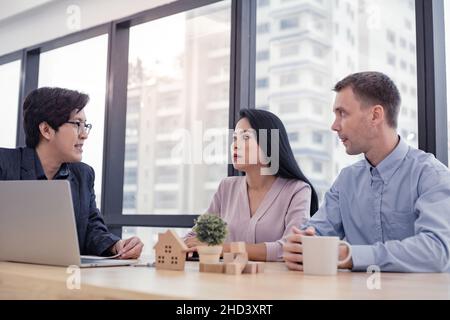 Kaufen oder verkaufen Haus Konzept, Verkaufsvertreter bieten Haus Kaufvertrag ein Haus zu Ehemann und Ehefrau zu kaufen. Die Verkaufsmitarbeiter bieten derzeit an Stockfoto
