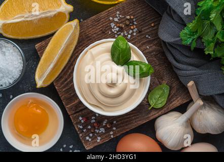 Mayonnaise und Zutaten zum Kochen: Eier, Zitrone und Butter auf schwarzem Hintergrund. Stockfoto