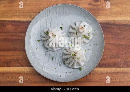 Nationale georgische Küche. Khinkali mit Fleisch. Khinkali auf dem Teller auf dem hölzernen Hintergrund. Draufsicht, Nahaufnahme mit Kopierbereich. Hochwertige Fotos Stockfoto