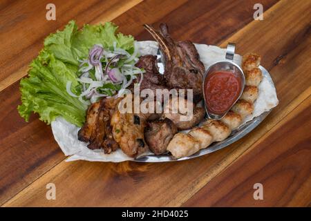 Verschiedene köstliche gegrillte Fleisch mit Salat und Zwiebeln. Gemischtes Grillfleisch mit Tomatensauce.Lamm, Huhn. Draufsicht, Nahaufnahme mit Kopierbereich. Stockfoto