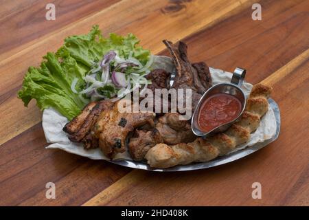 Verschiedene köstliche gegrillte Fleisch mit Salat und Zwiebeln. Gemischtes Grillfleisch mit Tomatensauce.Lamm, Huhn. Draufsicht, Nahaufnahme mit Kopierbereich. Stockfoto