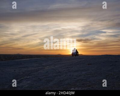 Wunderschöne Aussicht auf Menschen Silhouetten beobachten den Sonnenuntergang in der Weißen Wüste in Ägypten Stockfoto
