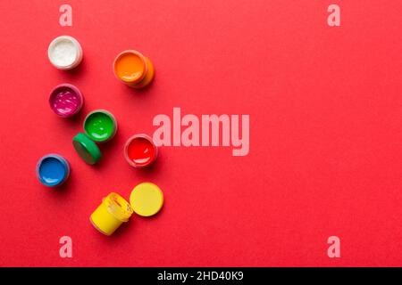 Gläser mit Gouache in verschiedenen Farben auf farbigem Hintergrund. Hobby Malerei. Draufsicht mit leerem Raum. Arbeitsplatz für Kreativität. Home Teaching concep Stockfoto