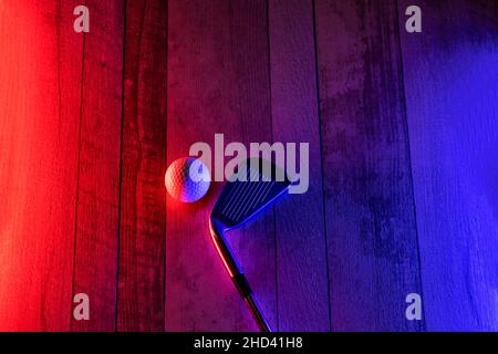 Golfschläger und weißer Ball auf Hartholz-Court-Boden mit Neonbeleuchtung. Blaues Neonbanner. Horizontales Sport-Thema Poster, Grußkarten, Header, Websi Stockfoto