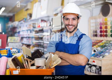 Lächelnder Handwerker mit gefalteten Armen in der Lackiererei Stockfoto
