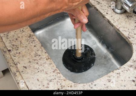 Nahaufnahme des Mannes mit einem Kolben, um das Spülbecken der Küche zu lösen. Stockfoto