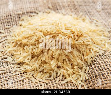 Ungekochte Basmati-Reis auf einem alten Sackleinen Hintergrund Stockfoto