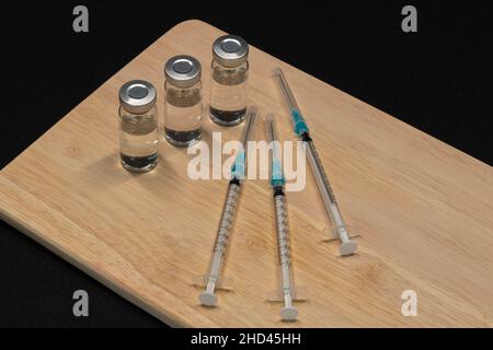 Medizinische Geräte, einschließlich Spritzen mit hypodermischen Nadeln mit Sicherheitsverschlüssen und Fläschchen mit einer klaren Flüssigkeit. Stockfoto