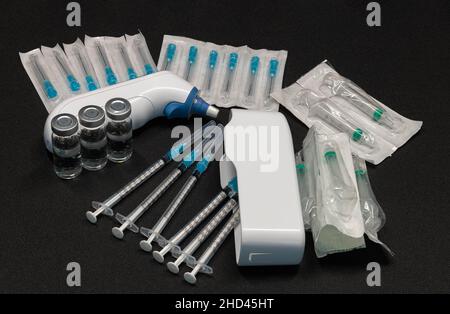 Medizinische Geräte, einschließlich Ohrthermometer, Spritzen mit hypodermischen Nadeln mit Sicherheitsverschlüssen und Fläschchen mit einer klaren Flüssigkeit. Stockfoto