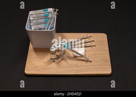 Medizinische Geräte, einschließlich Spritzen mit hypodermischen Nadeln mit Sicherheitsverschlüssen und Fläschchen mit einer klaren Flüssigkeit. Stockfoto