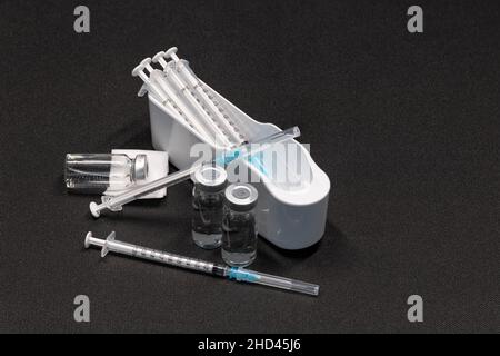 Medizinische Geräte, einschließlich Spritzen mit hypodermischen Nadeln mit Sicherheitsverschlüssen und Fläschchen mit einer klaren Flüssigkeit. Stockfoto