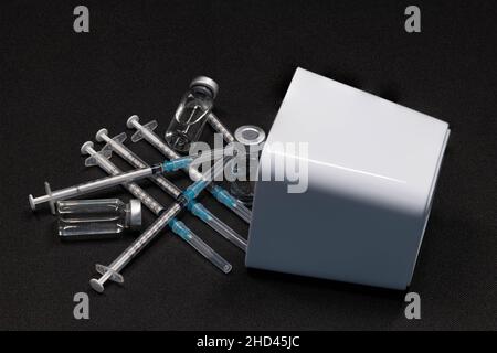 Medizinische Geräte, einschließlich Spritzen mit hypodermischen Nadeln mit Sicherheitsverschlüssen und Fläschchen mit einer klaren Flüssigkeit. Stockfoto