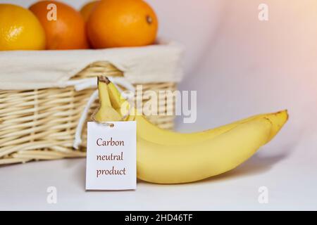 Kohlenstoffneutrales Produktetikett auf Bananen. CO2-Kennzeichnung. Korb mit Orangen auf dem Hintergrund. Netto kohlenstofffrei, emissionsfrei. Bio-Landwirtschaftsprodukte aus Stockfoto