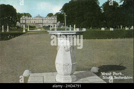 Antike Postkarte mit dem Titel „Wrest Park, Silsoe, Bedfordshire“. Zeigt die verzierte Sonnenuhr auf dem Gelände des Wrest Park, einem Landgut in Silsoe, Bedfordshire, England. Das Herrenhaus und Statuen sind im Hintergrund zu sehen. Stockfoto