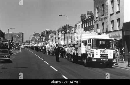 Eine Demonstration von Mitgliedern der Southwark-Niederlassung der britischen Gewerkschaft, NALGO (National and Local Government Officers' Association) und dem Southwark Trades Council, die gegen die Entlassung eines Arbeitnehmers aus dem Southwark London Borough Council protestierten. Mitte 1980s. Das Foto zeigt die marschierenden Demonstranten entlang der Walworth Road, Southwark, London. Die Demonstranten folgen einem LKW-Wagen, der mit Plakaten und Luftballons geschmückt ist. Sie tragen die Transparente der Southwark Branch NALGO und des Southwark Trades Council und Plakate mit dem Slogan „Who Cares About Workers? – Nicht Der Rat Von Southwark“. Stockfoto