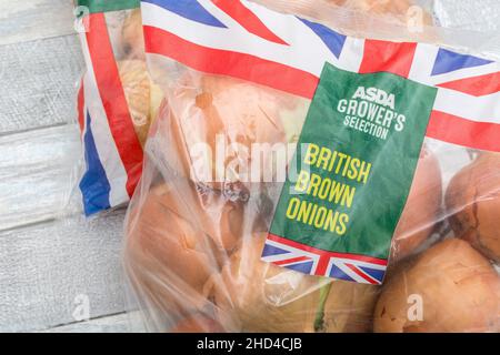 BRAUNE Zwiebeln/Allium cepa in Kunststoffpackungen. Auch gelbe Zwiebeln genannt. Für gängige Küchenzutaten, Union Jack auf Lebensmittelverpackungen Stockfoto