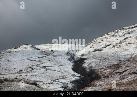 Gefährliche Haarnadelkurven auf Hardknott Pass bei schneebedecktem Wetter von Cockley Beck, Winter, Lake District National Park, Cumbria, England Stockfoto