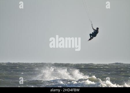 Fliegender, fliegender Kite-Surfer, der die Wellen im Solent, Avon Beach, Christchurch, Großbritannien, springt Stockfoto