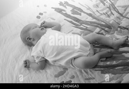 Neugeborenes Mädchen liegt auf dem Bett. Das Baby ist gerade zwei Wochen alt geworden. Pflegekonzept für Neugeborene. Stockfoto